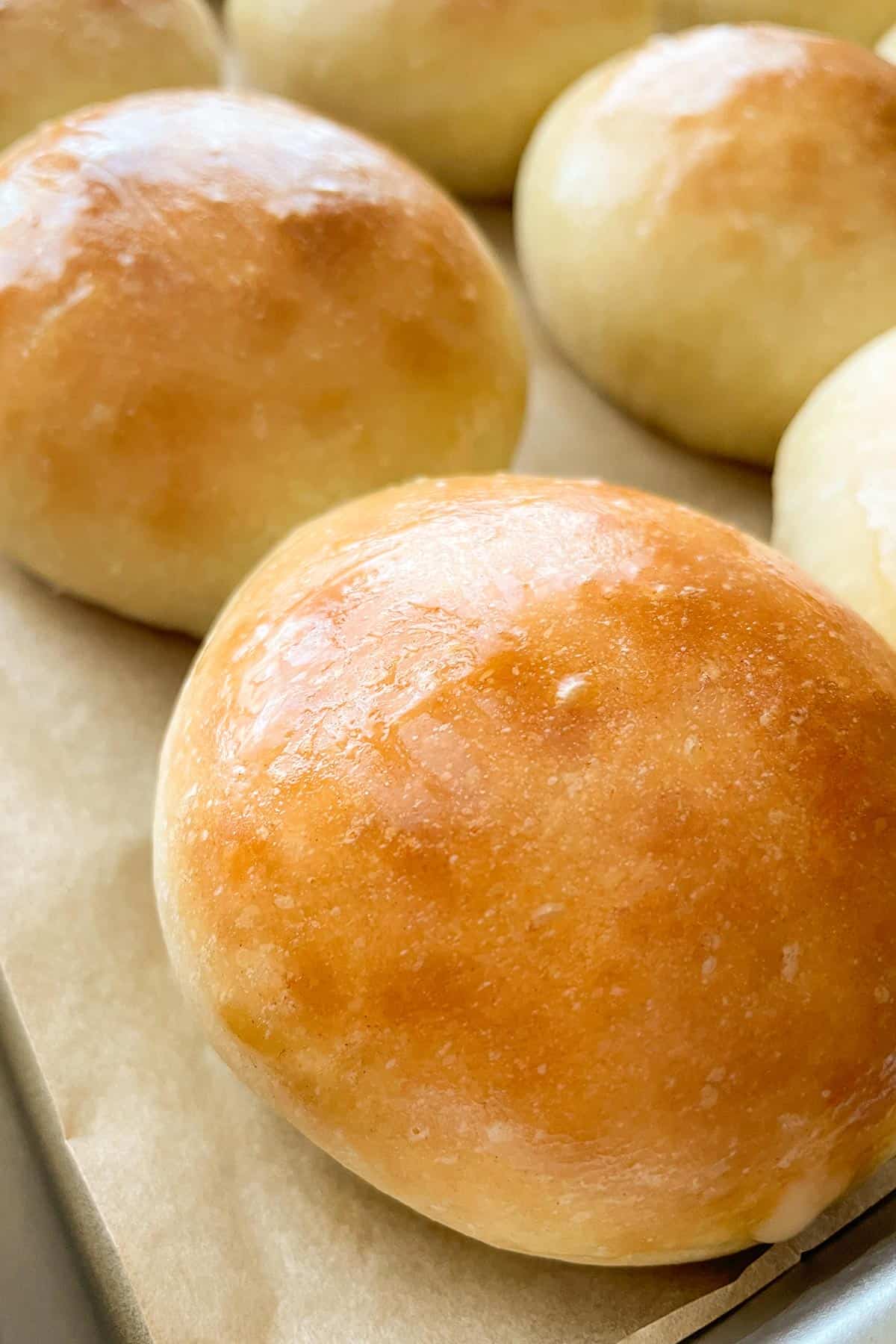 potato bread rolls brushed with butter on a tray.