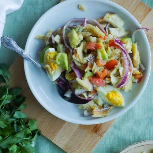 a plate full of cod fish salad on a cutting board.