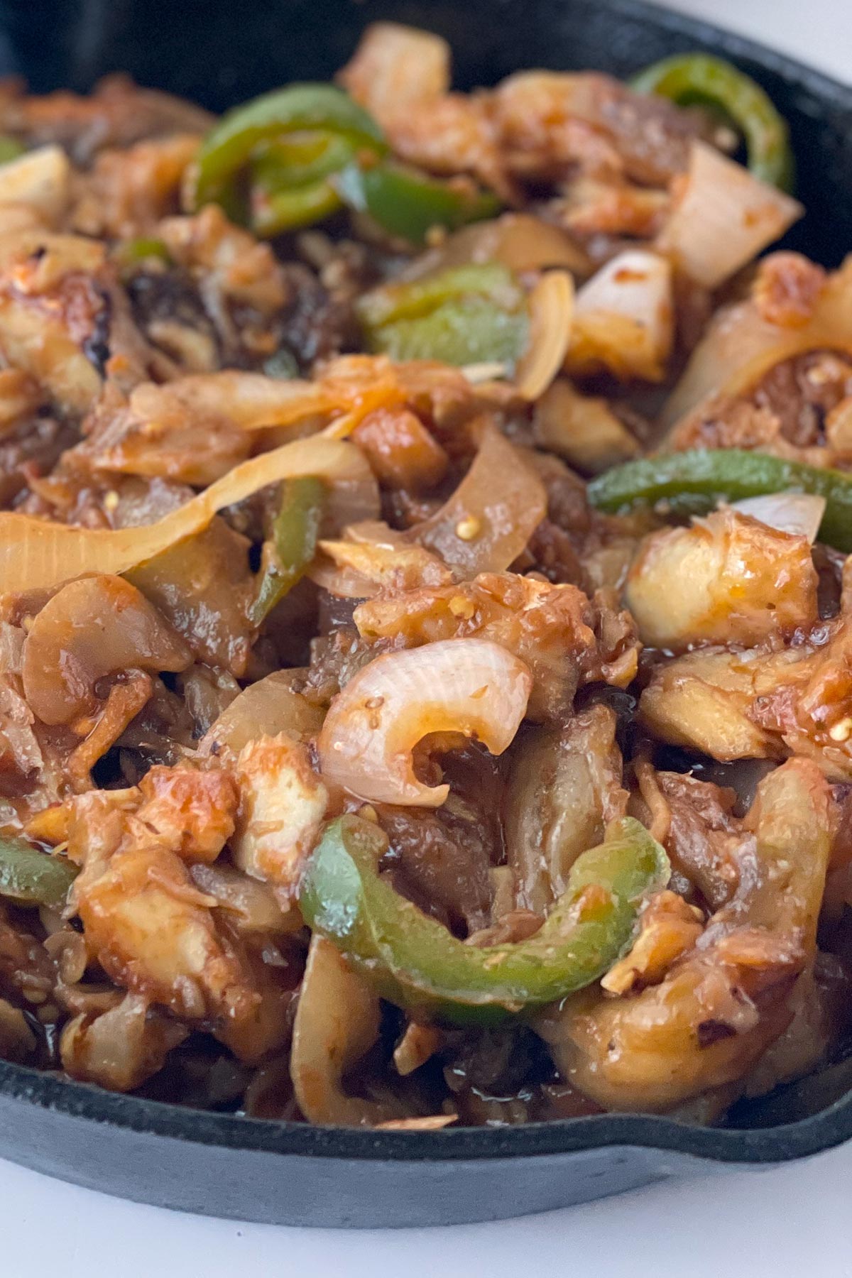 close up of eggplant with salted codfish and green peppers and onions.