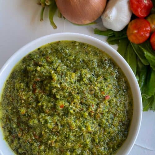 a white bowl full of sofrito and a few vegetables on the side.