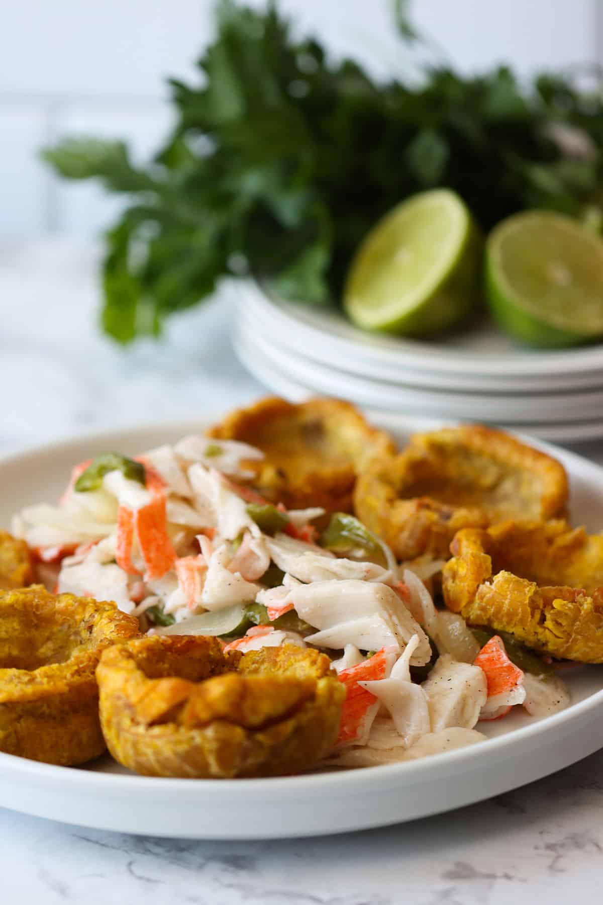 ensalada de king crab- king crab salad with plantain cups on the side and limes on the background.