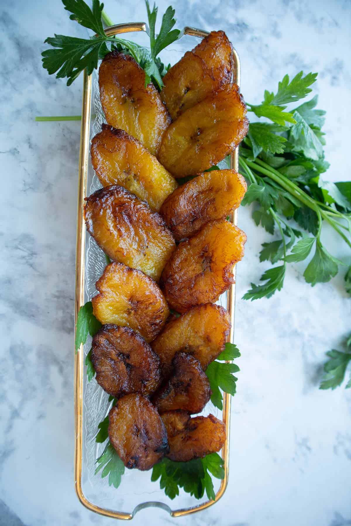 fried plantains in a long glass dish garnished with parsley.