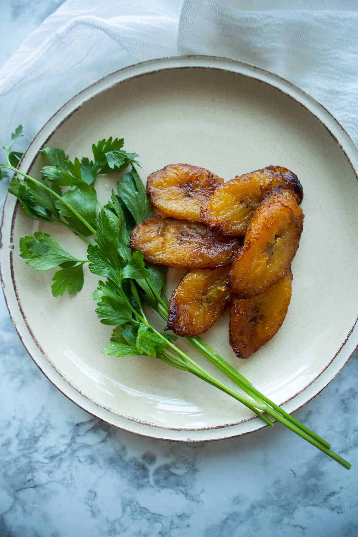 amarillos-platanos maduros sobre un plato con perejil de decoracion.