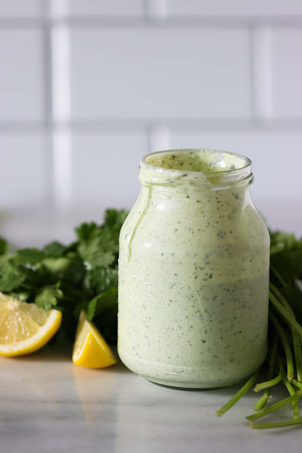 salsa de cilantro con cilantro y rodajas de limones al lado.