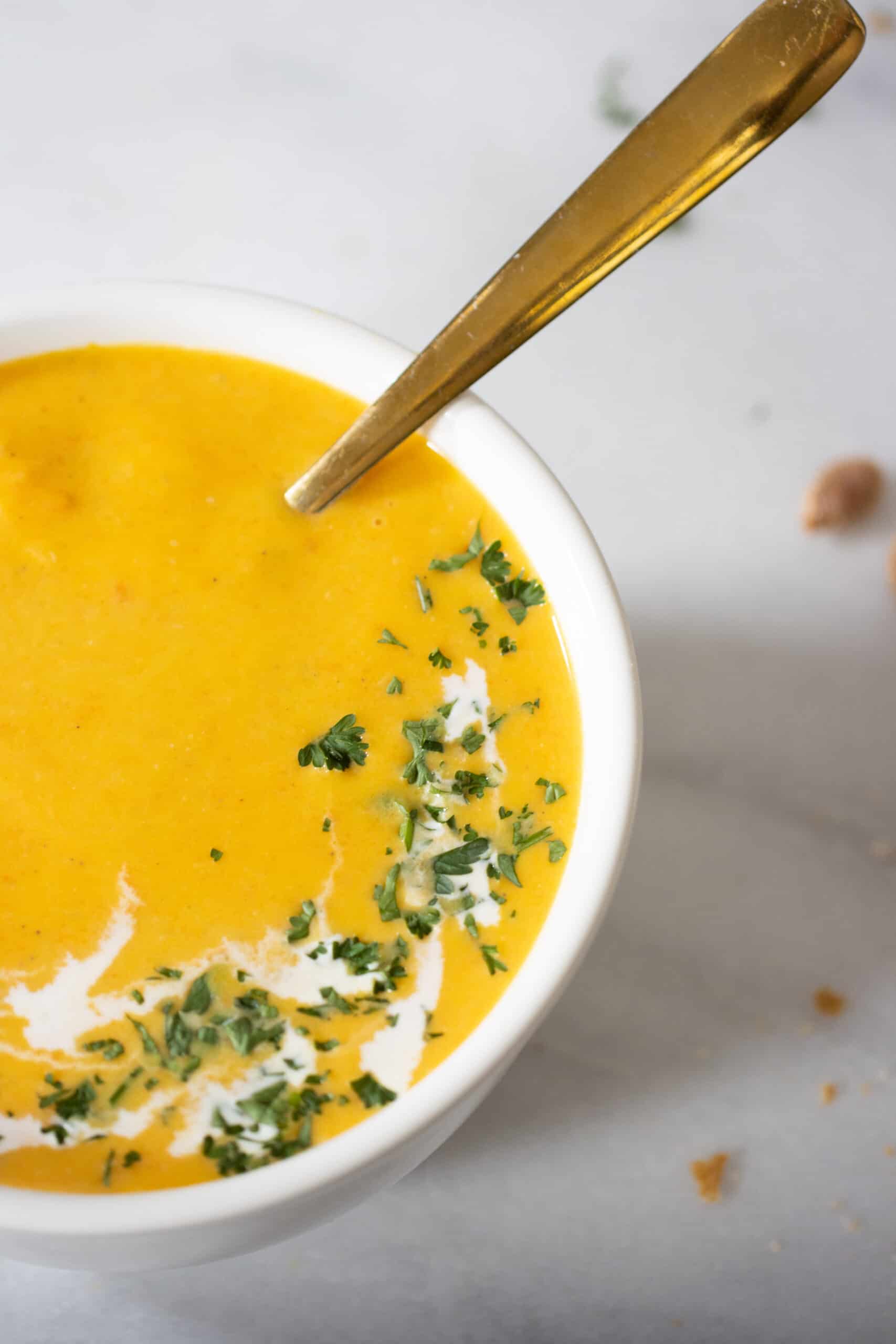 un plato lleno de sopa de calabaza con una cuchara.