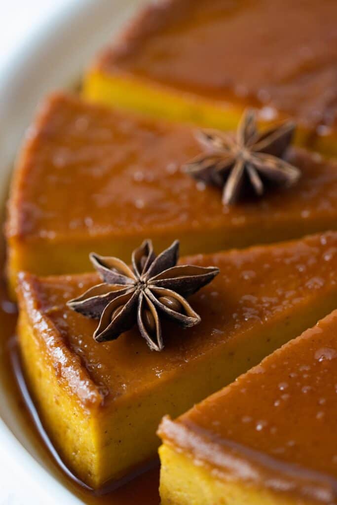 close up view of a few pieces of pumpkin flan with a star anise as garnish on top.
