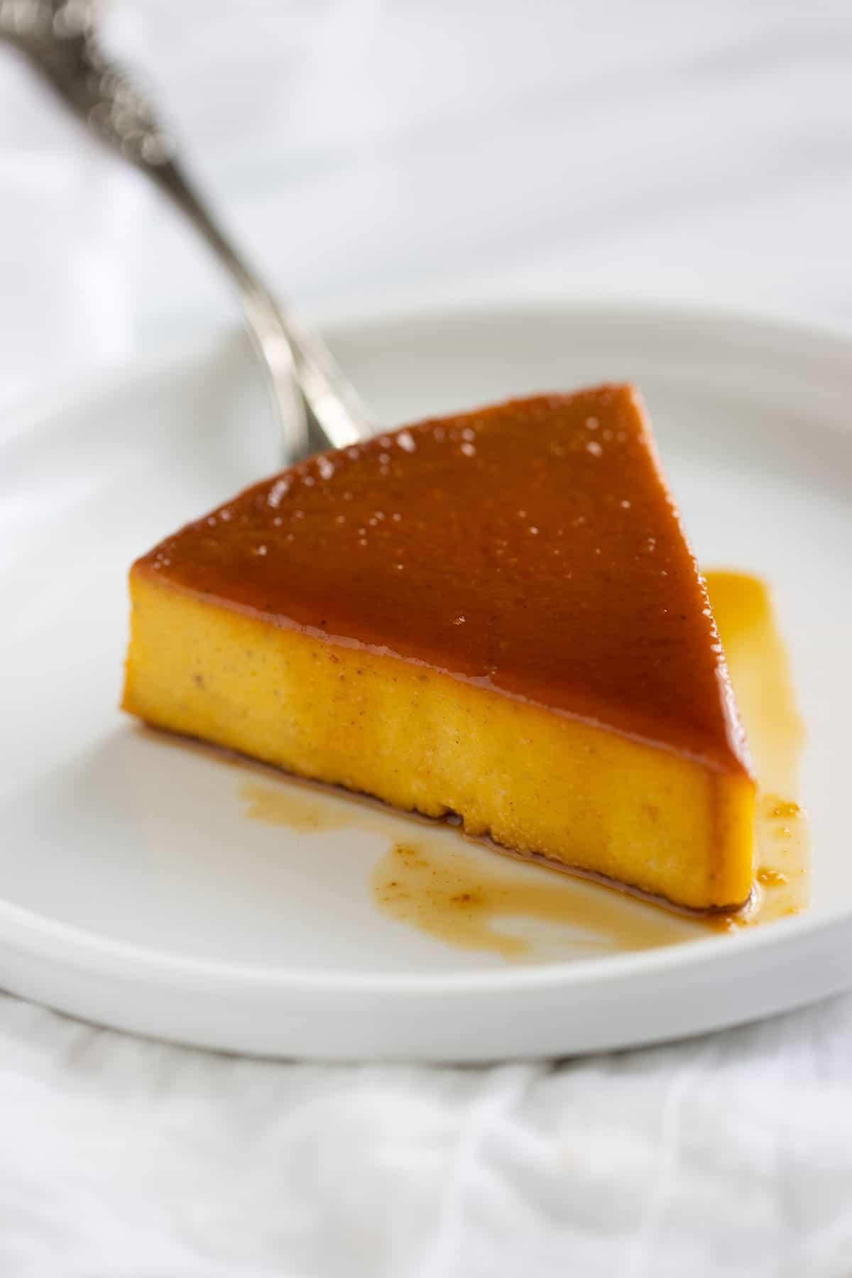 un pedazo de flan de calabaza sobre un plato blanco.