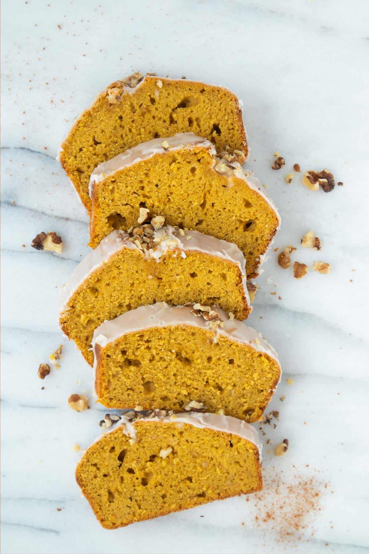 pumpkin loaf cake in slices with walnuts pieces around.
