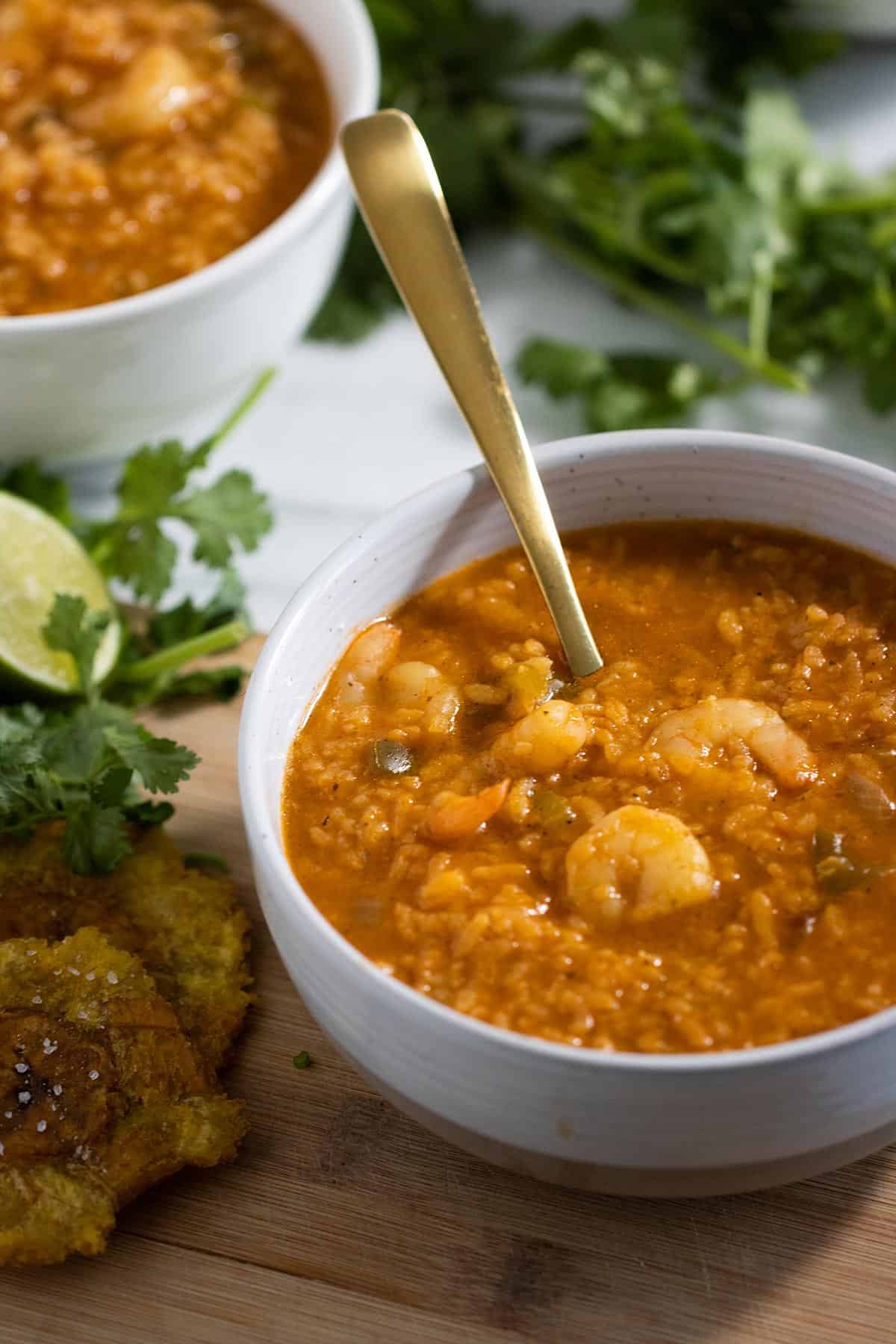 two plates with asopao de camarones or shrimp soup with some tostones on the side.