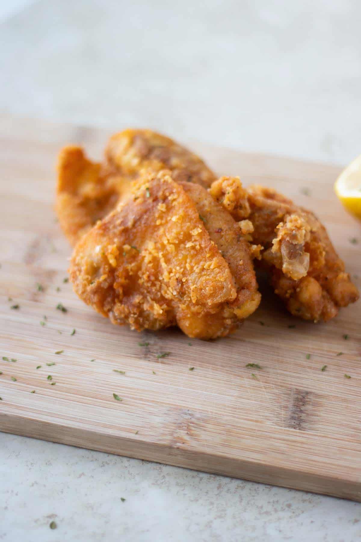 two pieces of chicharrones de pollo over a cutting board.