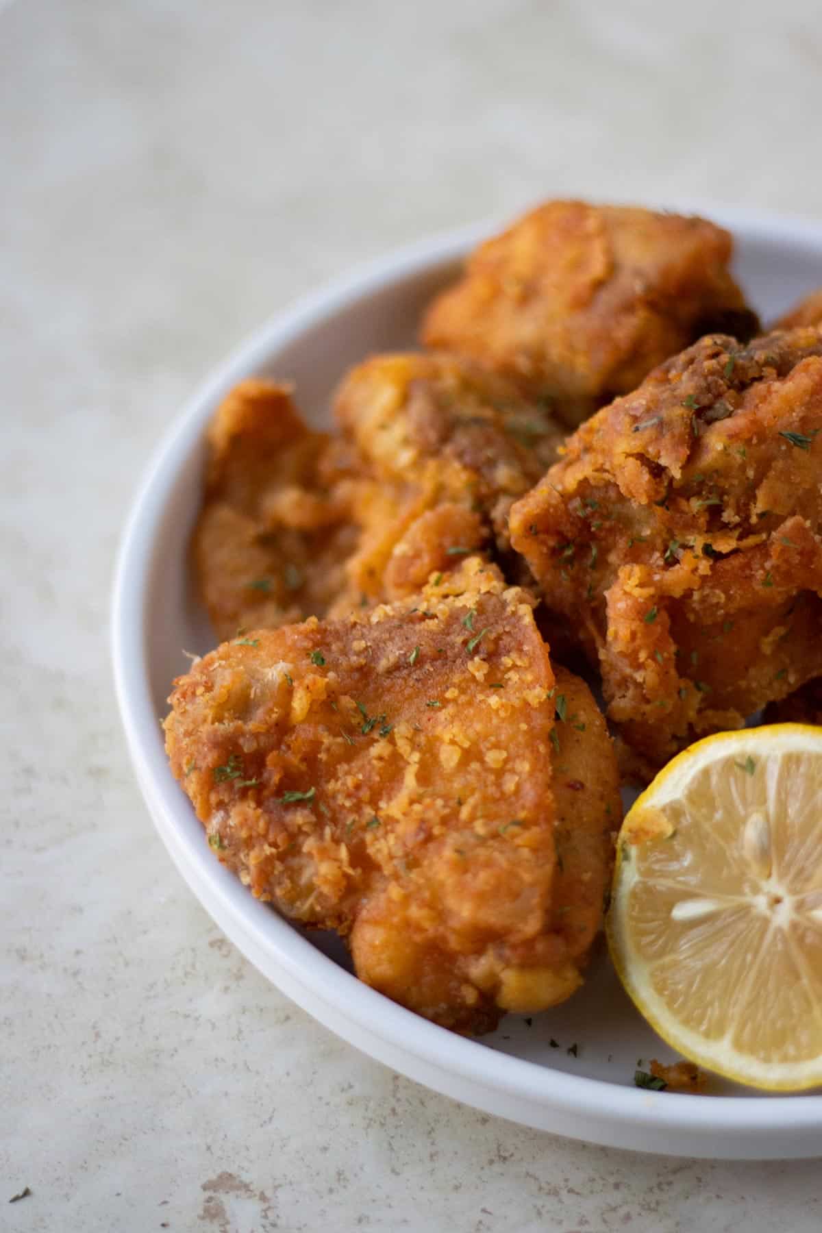 plato blanco con chicharron de pollo y medio limon al lado.