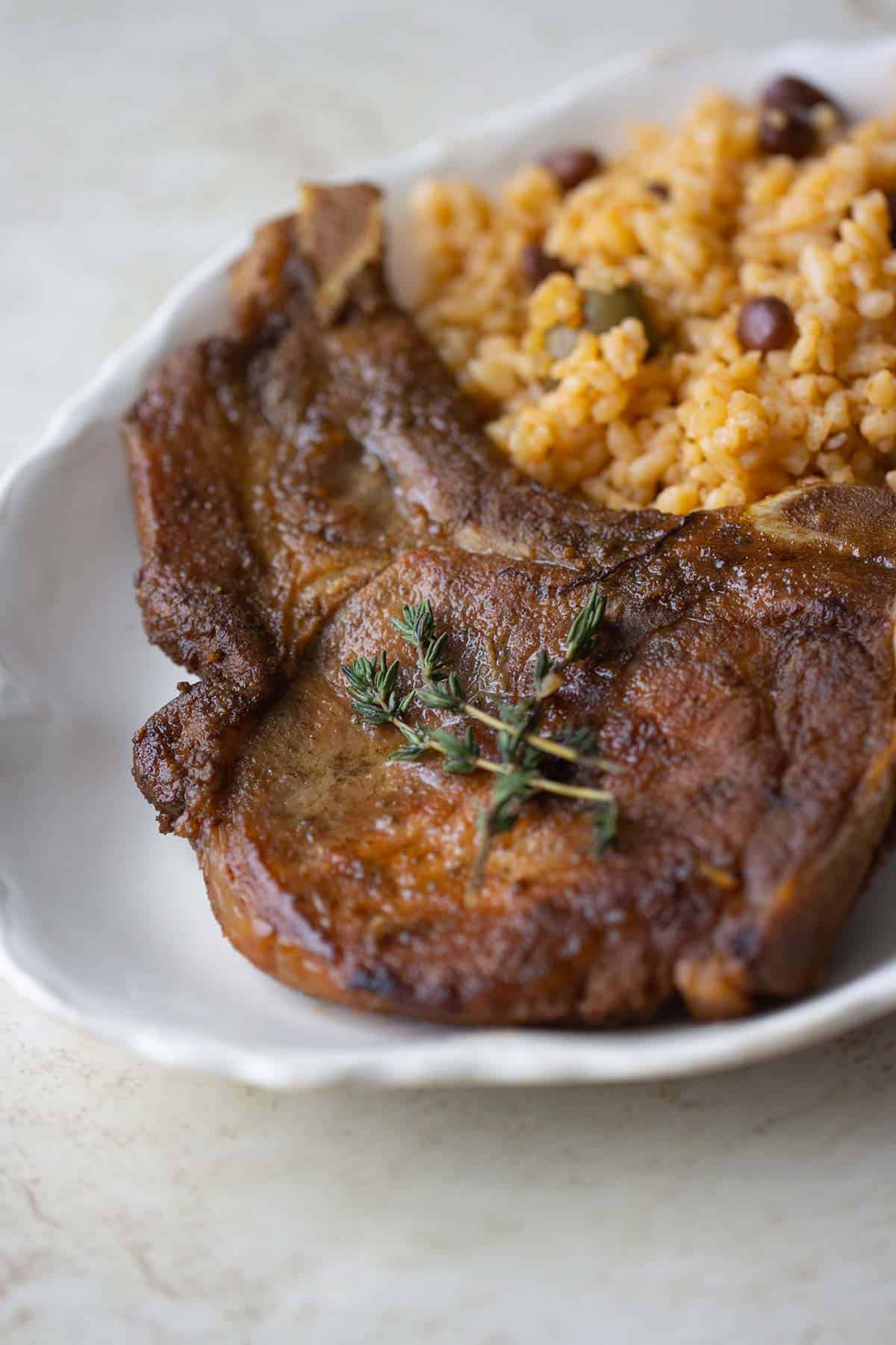 a plate with a fried pork chop with rice and beans.