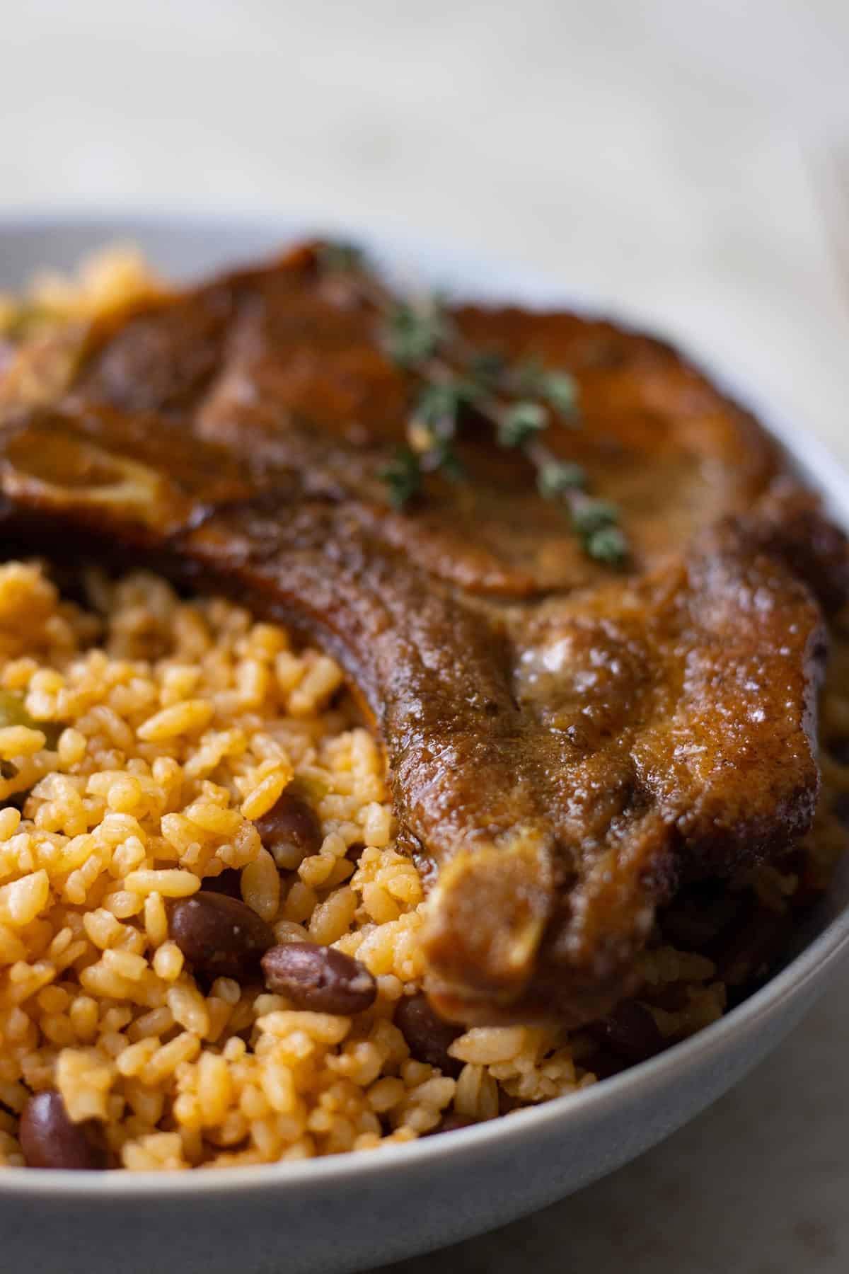 a close up of  a plate with puerto rican rice and beans and a fried pork chop.