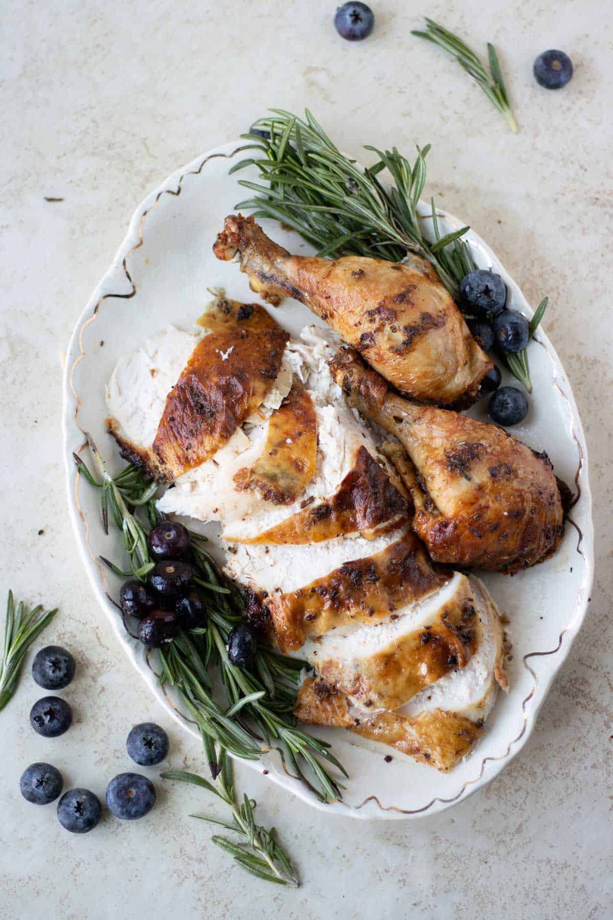 pollo asado cortado sobre un plato con romery y bluberries