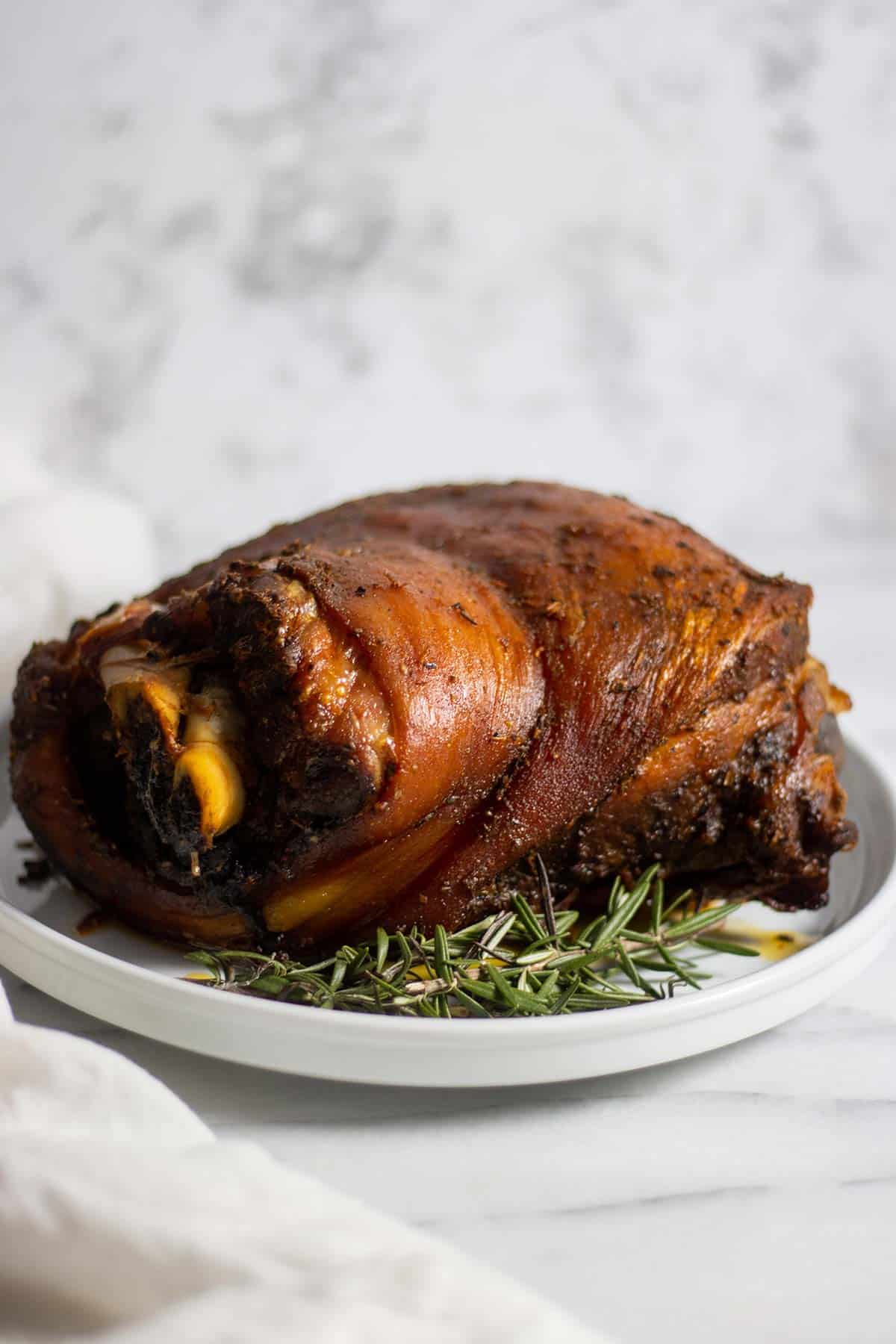 puerto rican pernil in a white plate with fresh thyme as garnish.