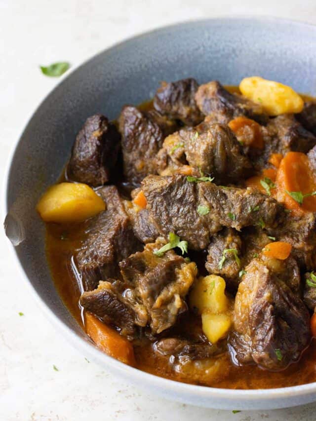 a light blue plate full of puerto rican carne guisada with carrots and potatoes.