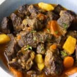 a light blue plate with puerto rican beef stew with carrots and potatoes.