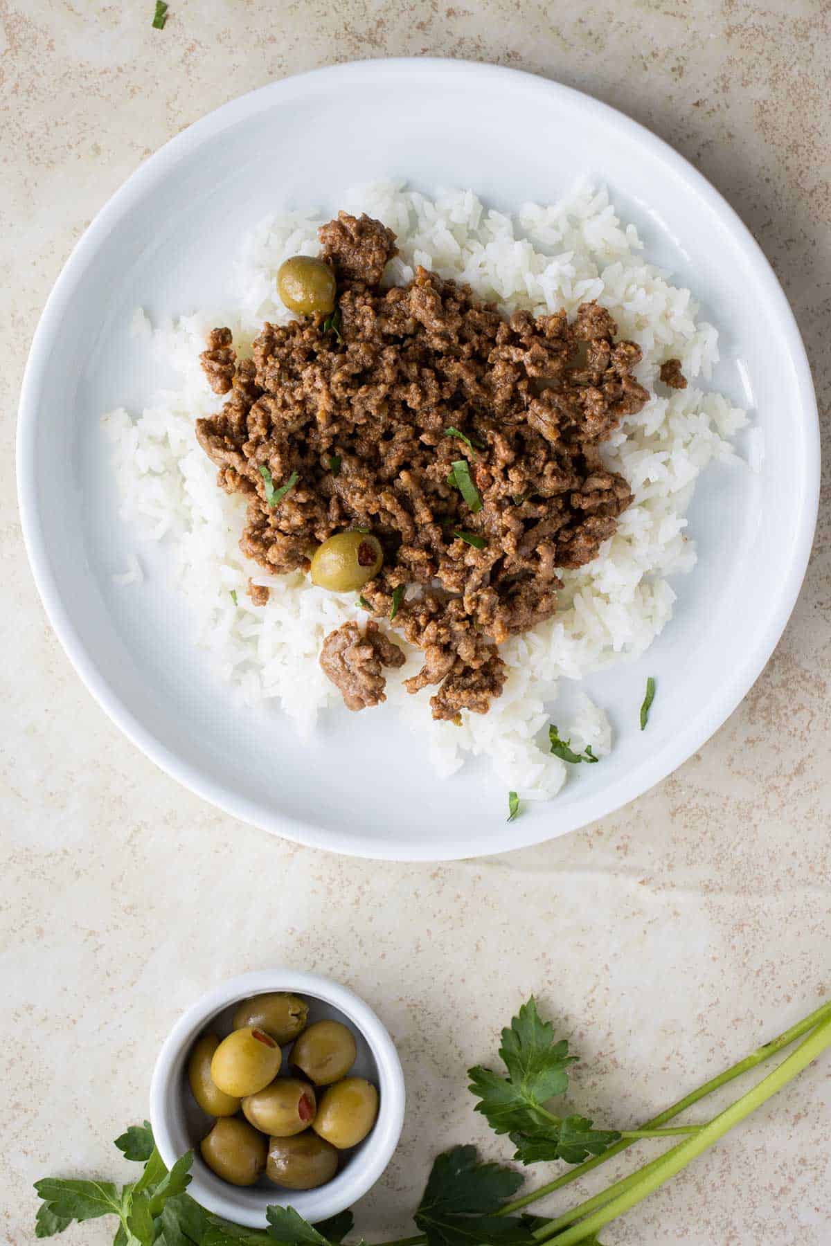 white plate wih white rice and puerto rican picadillo.