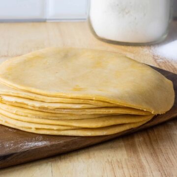masa de empanadillas made into disk on a stack with a jar of flour in the background.