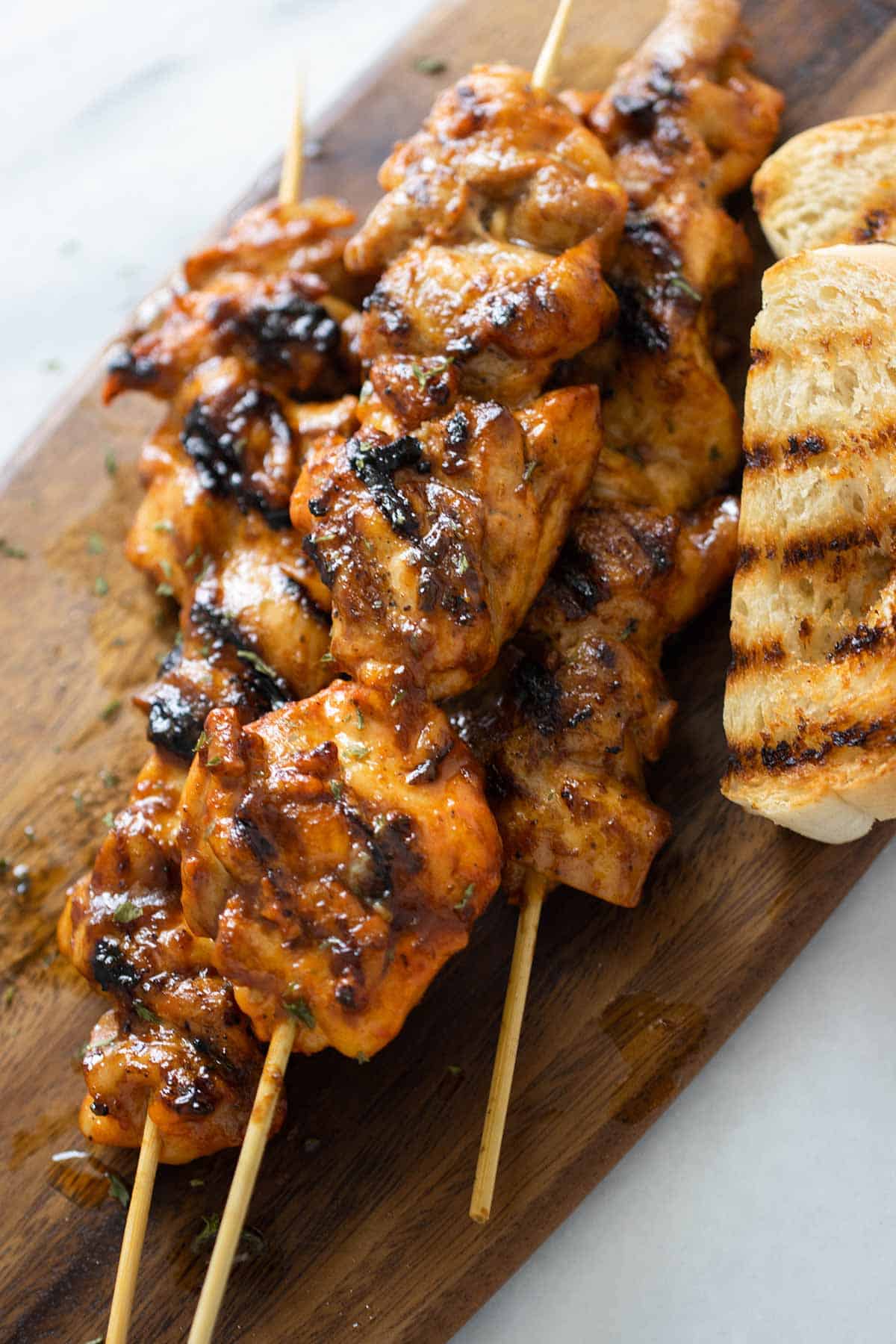 3 chicken pinchos with pan sobao over a wood cutting board.