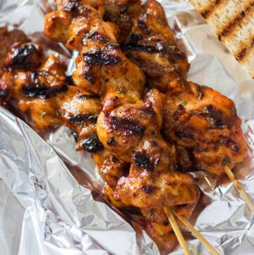3 chicken skewers with bread on foil.