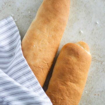 2 loafs of puerto rican style pan sobao with a line towel around it.