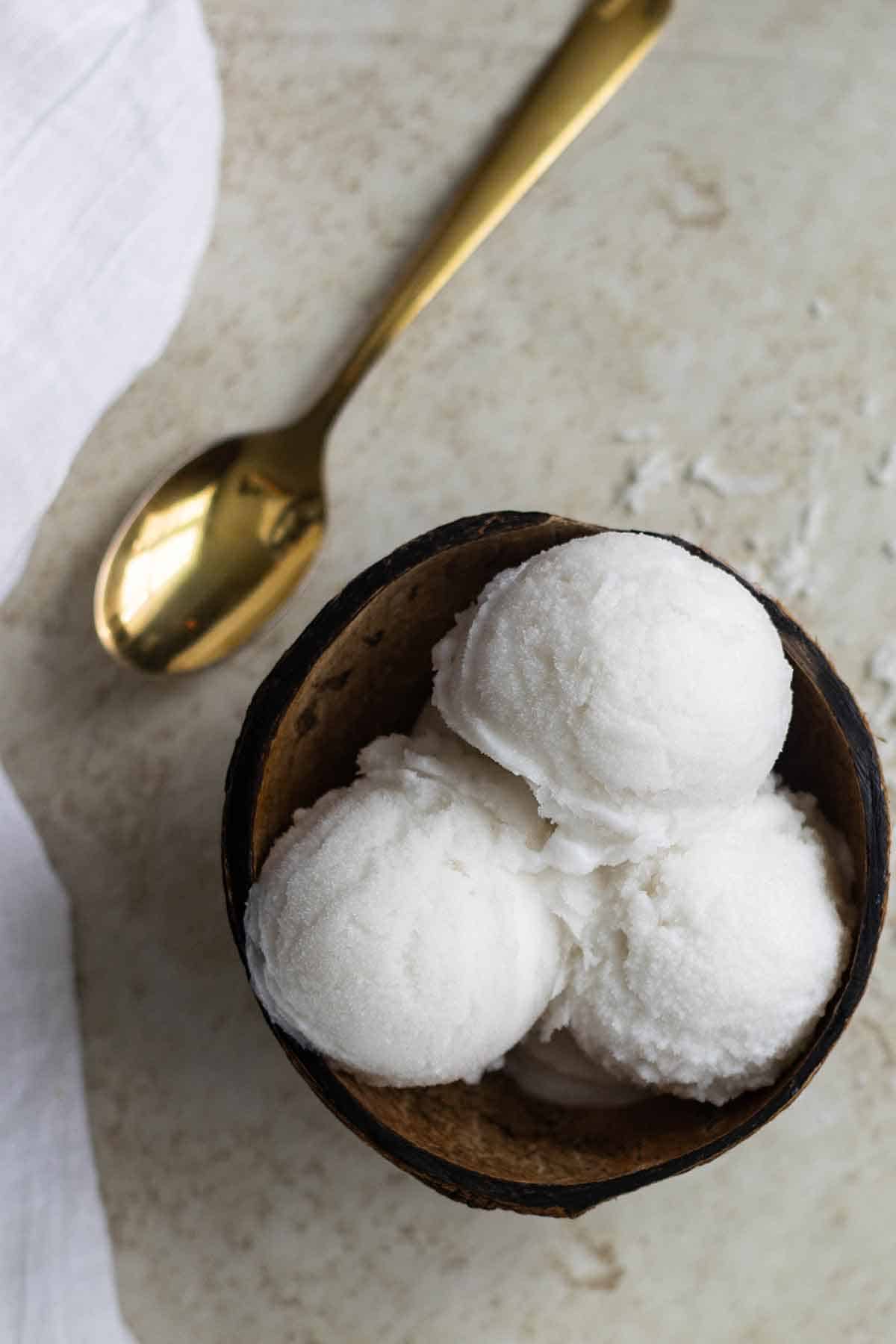 vista aerea de un helado de coco junto a una cuchara de oro al lado.