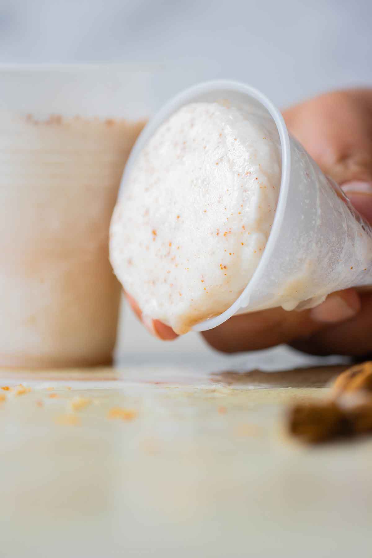 a hand holding a cup of a melting limber de coco.