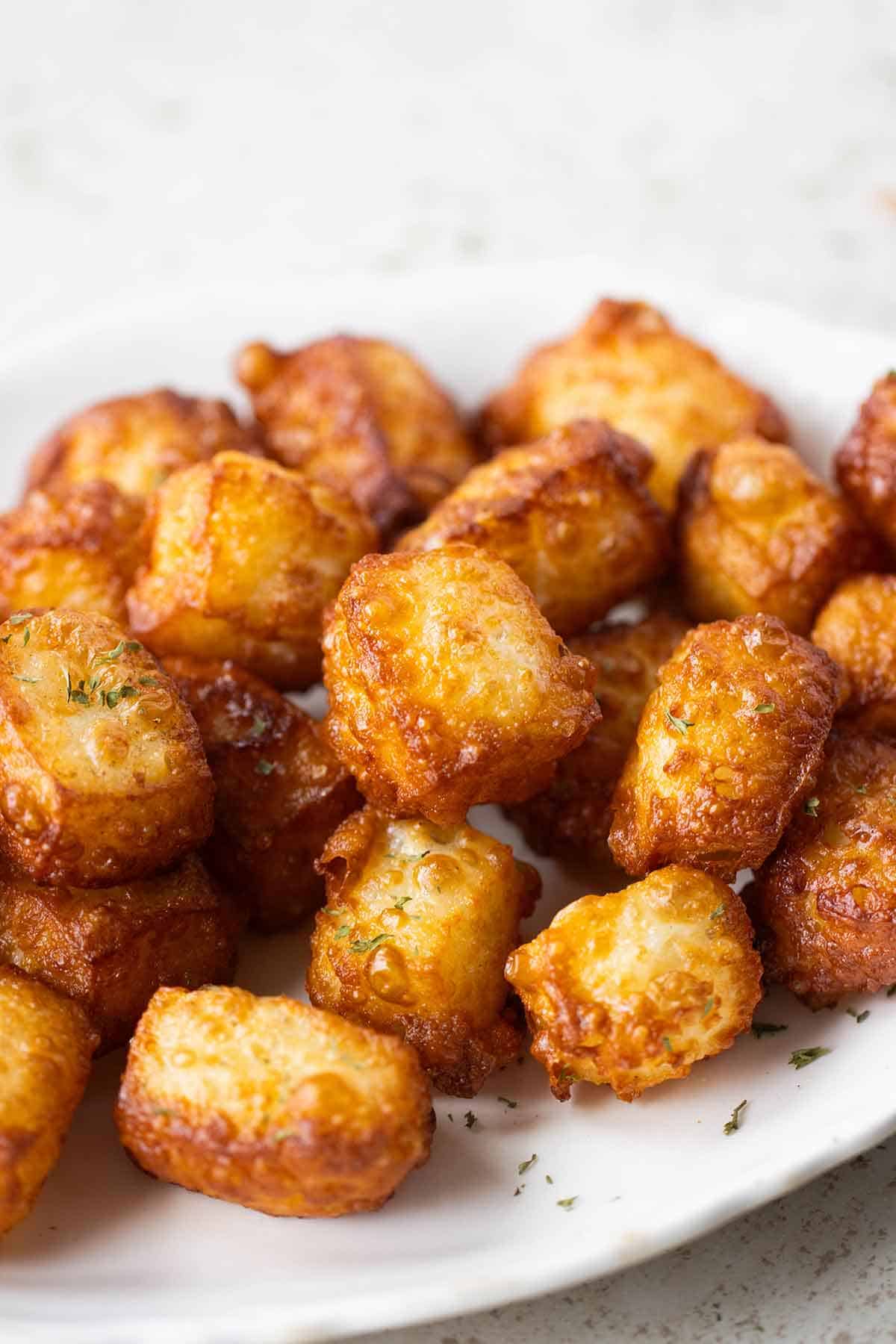 a white plate full of queso frito and garnished with dried parsley.