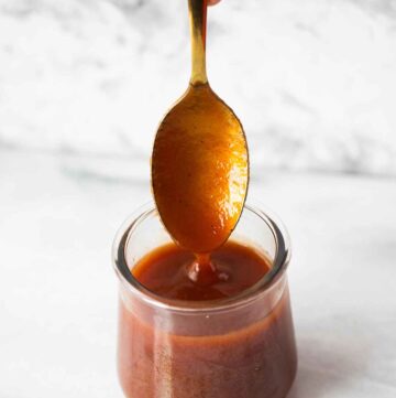 a jar and spoon filled with guava sauce.