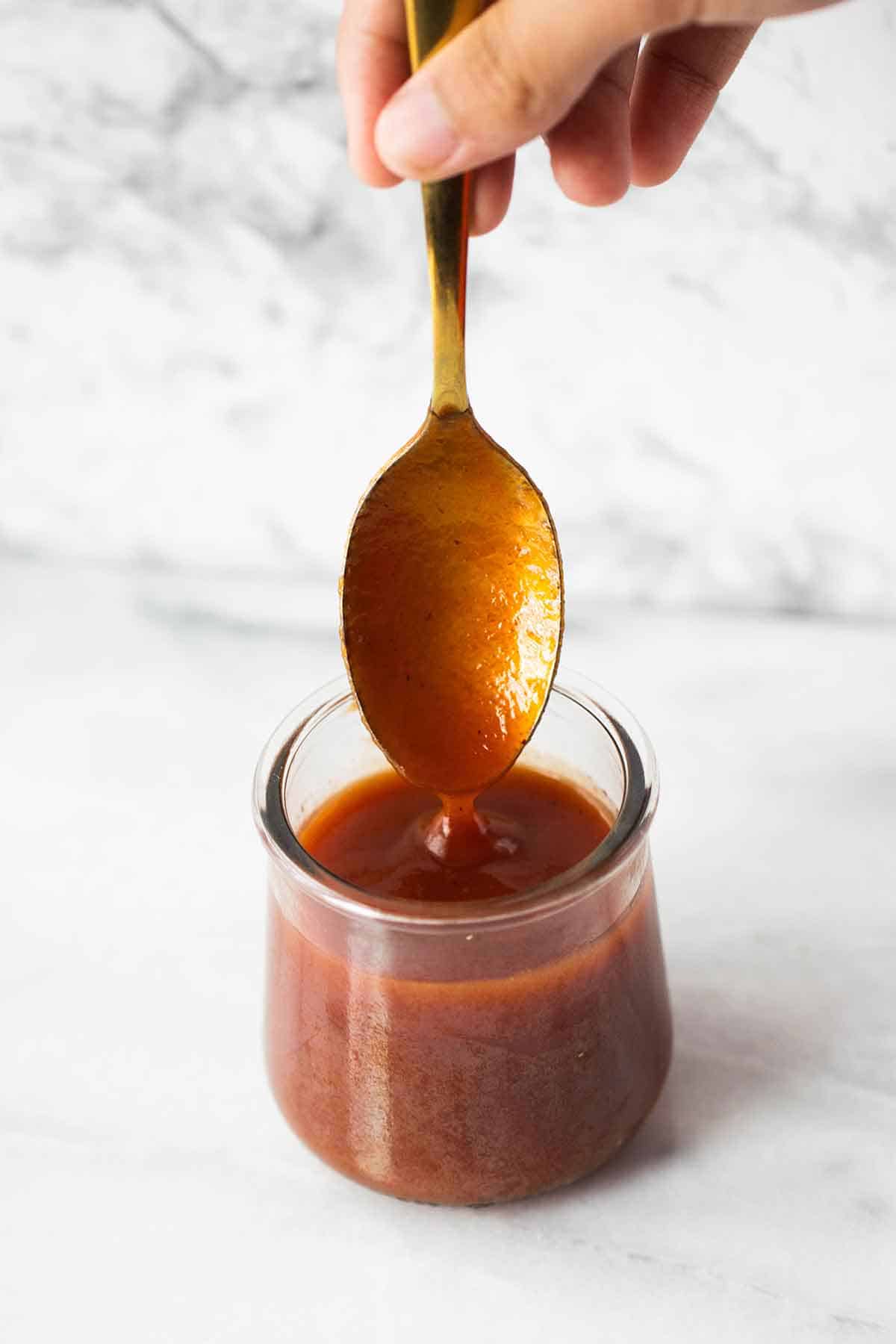 a jar and spoon filled with guava sauce.