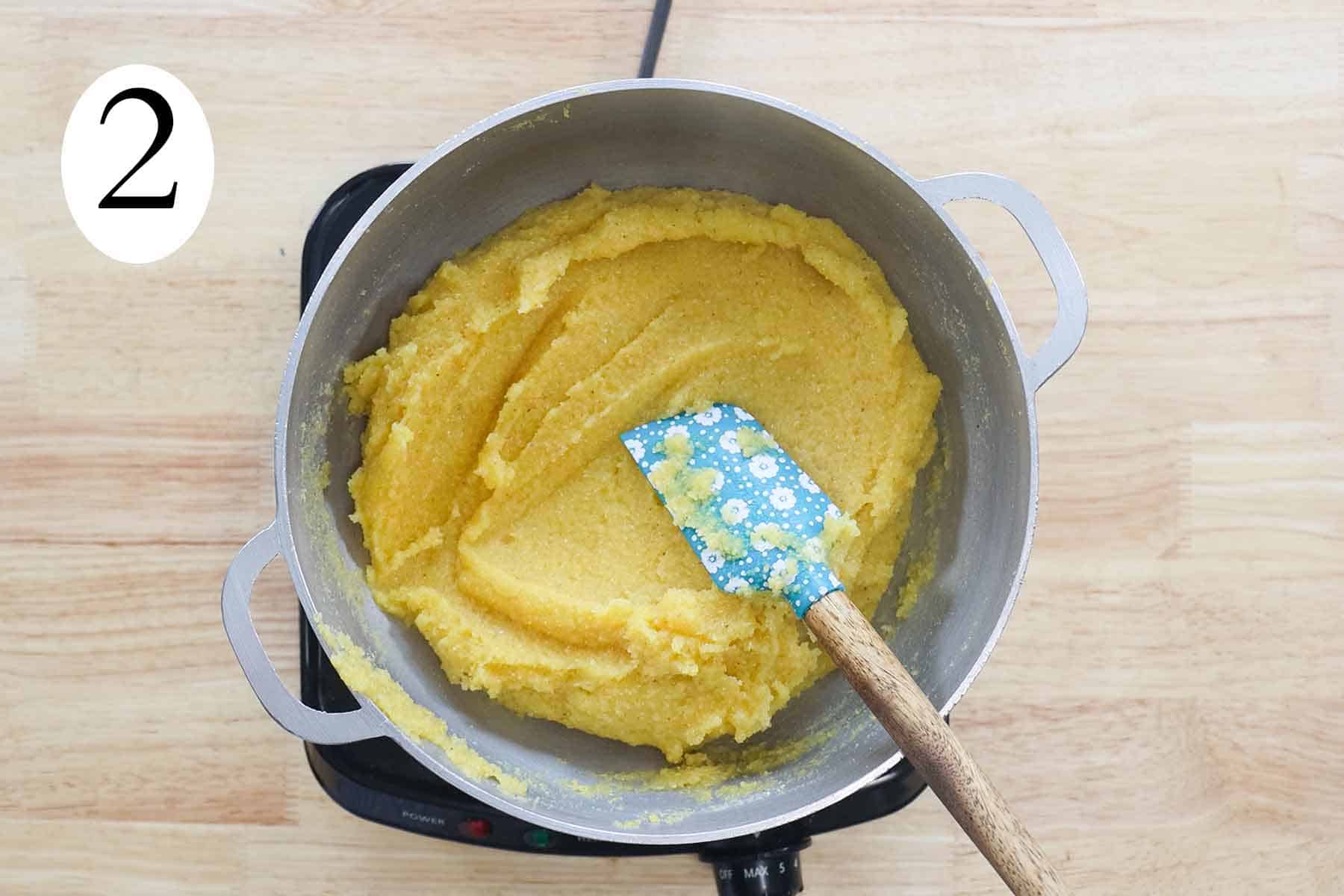 a pot with cooked cornmeal and a spatula.