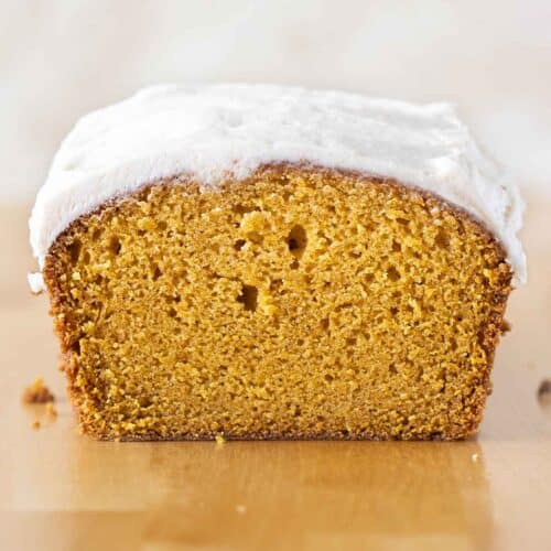 a loaf of pumpkin cake with frosting on a countertop.