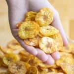 a hand holding a bunch of platanutres or plantain chips.