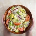 a pair of hand holding a bowl with ensalada verde.
