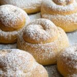 6 mallorcas with powder sugar on a baking tray.