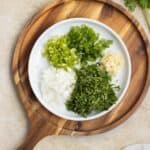 a plate full of cubbed aromatic vegetables needed to make a sofrito substitute over a wooden board.