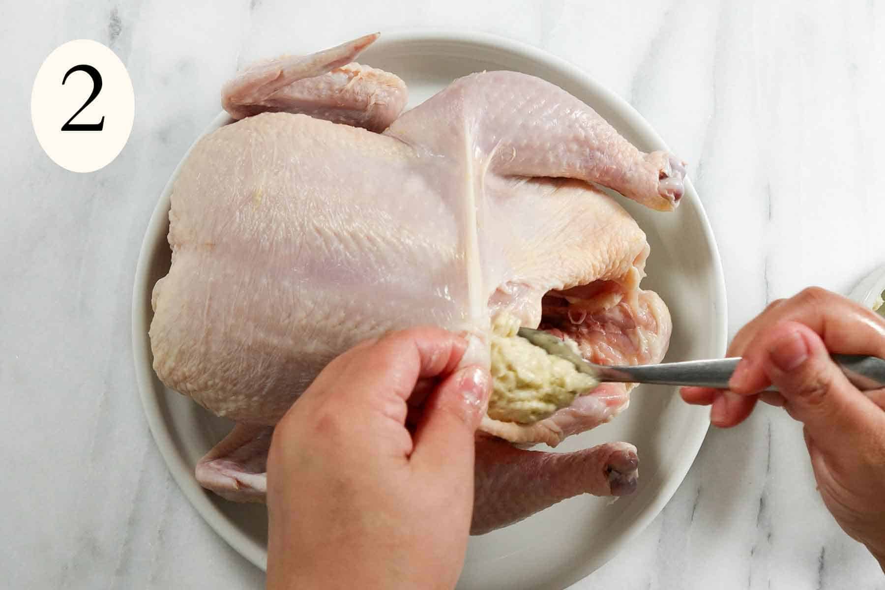 stuffing a whole chicken with seasoned butter.