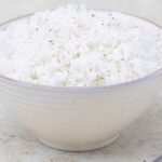 a bowl full of puerto rican white rice garnished with some dried parsley.
