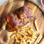 half of pollo a la brasa with french fries and sauces on the side.