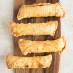 4 puerto rican cheese dogs on a wood cutting board.