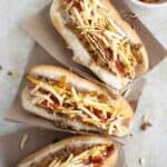 3 hotdogs made in a puerto rican style with a dish of saute onions on the side.