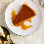 a piece of passion fruit flan with gold spoons on the side.