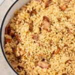 a big pot with a rice with bacon and onion.