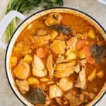 a pan with puerto rican fricase de pollo and on the side a plate of white rice and cilantro.