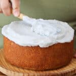 a person spreading a stable buttercream over a cake.