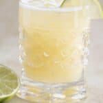 a cup of pineapple lemonade with a piece of lime on the side.
