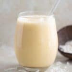 a glass cup with a cocnut and passion fruit smoothie.