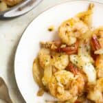 a plate and pan with a puerto rican style garlic butter shrimp or camarones al ajillo.