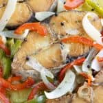 3 pieces of sierra en escabeche with onions and peppers.